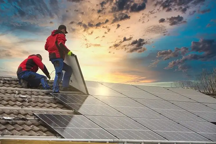Two people installing solar panels on roof 2 Two people installing solar panels on roof